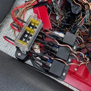 Schwarzer 3D-gedruckter Relais- und Sicherungsträger mit eingesetzten elektrischen Komponenten.